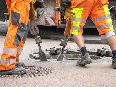 Crew jackhammering old asphalt surface during full replacement