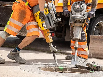 Road construction workers breaking asphalt with jackhammers