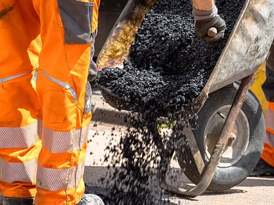 Close-up of workers dumping hot asphalt at paving site