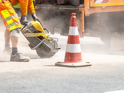 Worker cutting asphalt with circular saw for crack repair